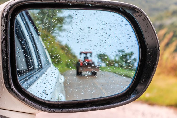Esőben haladó traktor a tükörben